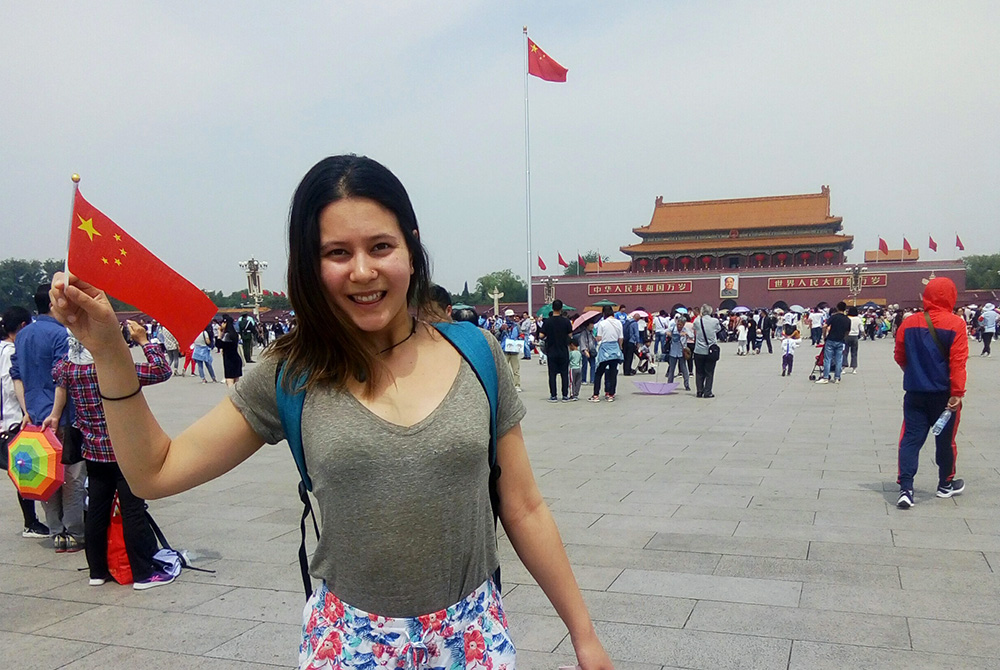 Emily Wilby waving a small Chinese flag in Tiananmen Square
