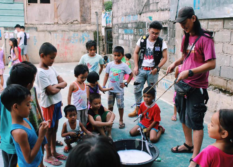 Kids are entertained in a slum by two older people