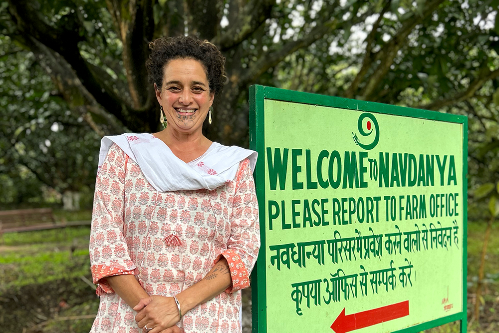 A woman standing in front of a sign saying welcome to Mavdanya