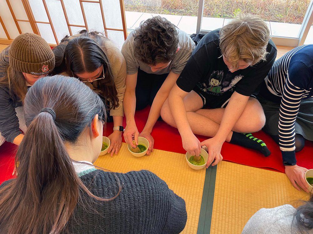 Awatapu College students sitting on tatami mats mixing macha paste in small bowls (Macha?) 