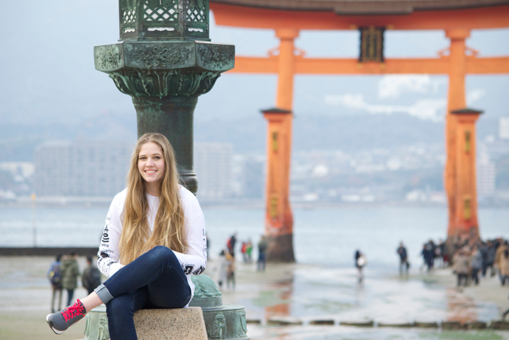 Woman sits in front of Japanese gate while on a Japan study grant