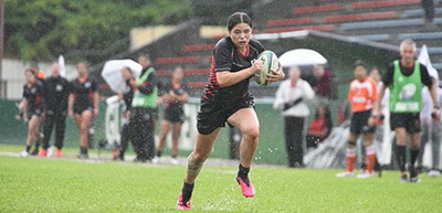 Manukura player Te Maia Sweetman running with the ball in the rain