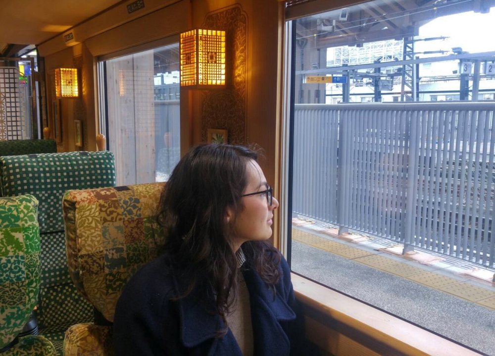 woman sits in train, looking out window