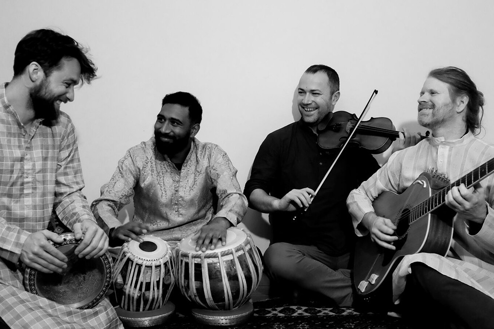 The Wellington contingent of Shades of Shakti - Thomas Friggens, Chetan Ramlu Tristan Carter and Justin 'Firefly Clark sitting on the ground with their instruments