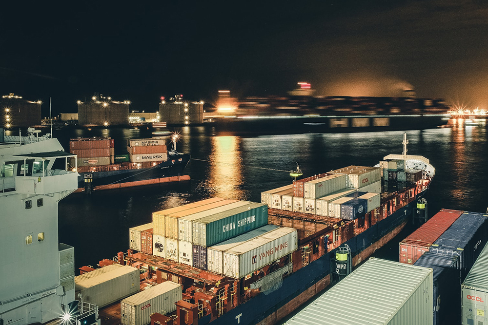 A ship carrying containers a a port at night