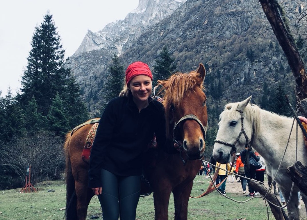 Caitlyn standing with horse in front of Chengdu mountain backdrop