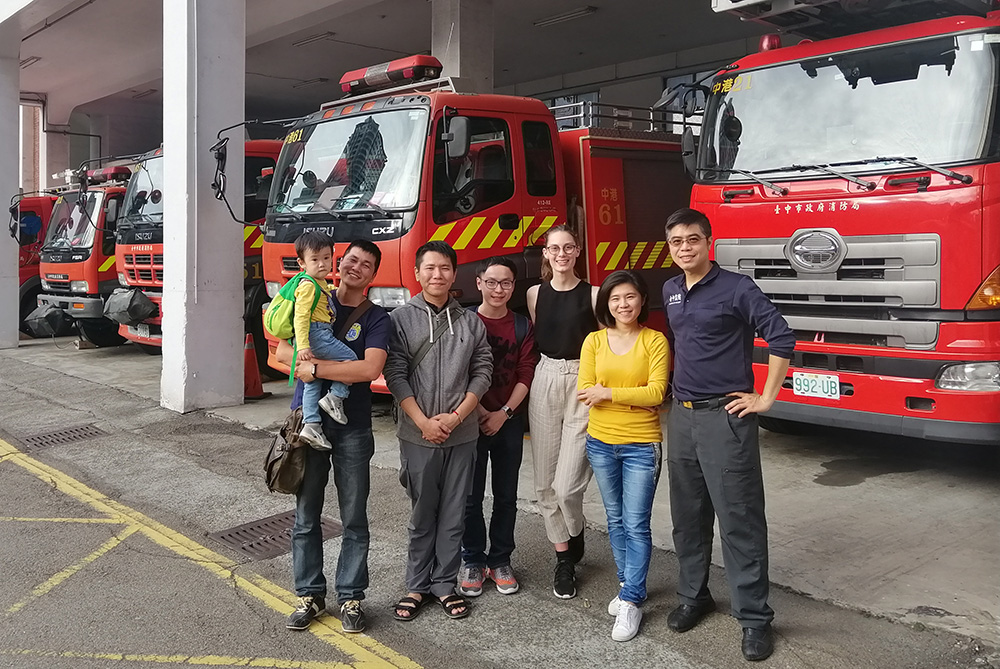 Monique with colleagues and firefighters in front of a fire station