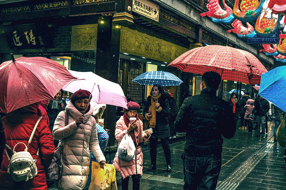 People carrying shopping and umbrellas walking on a street