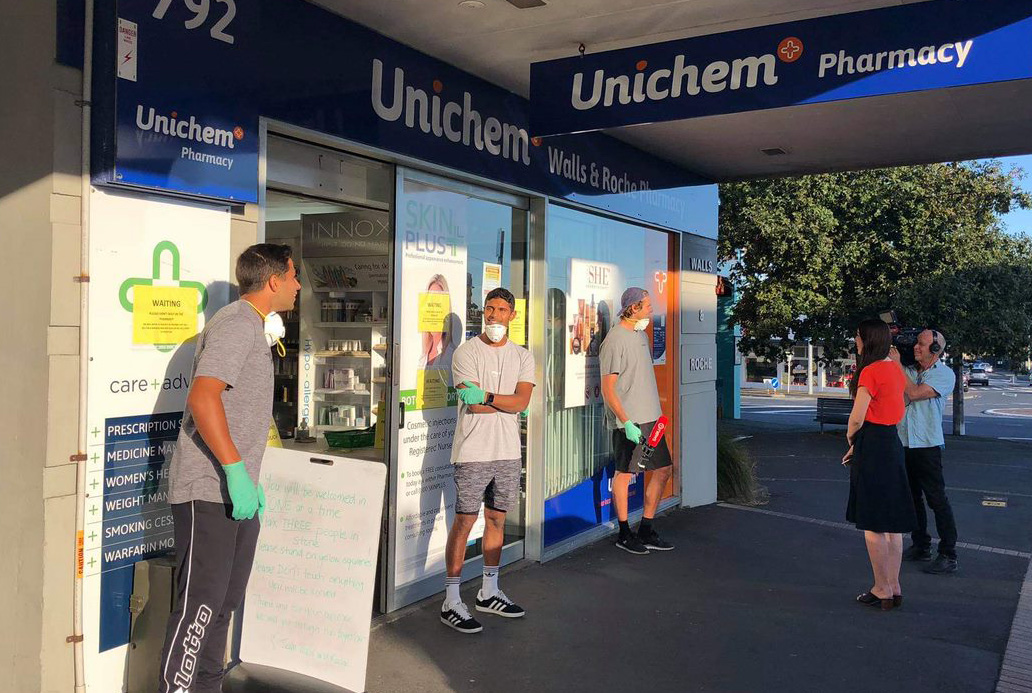 Richard talking to a reporter outside a pharmacy watched on by two fellow Black Sticks players