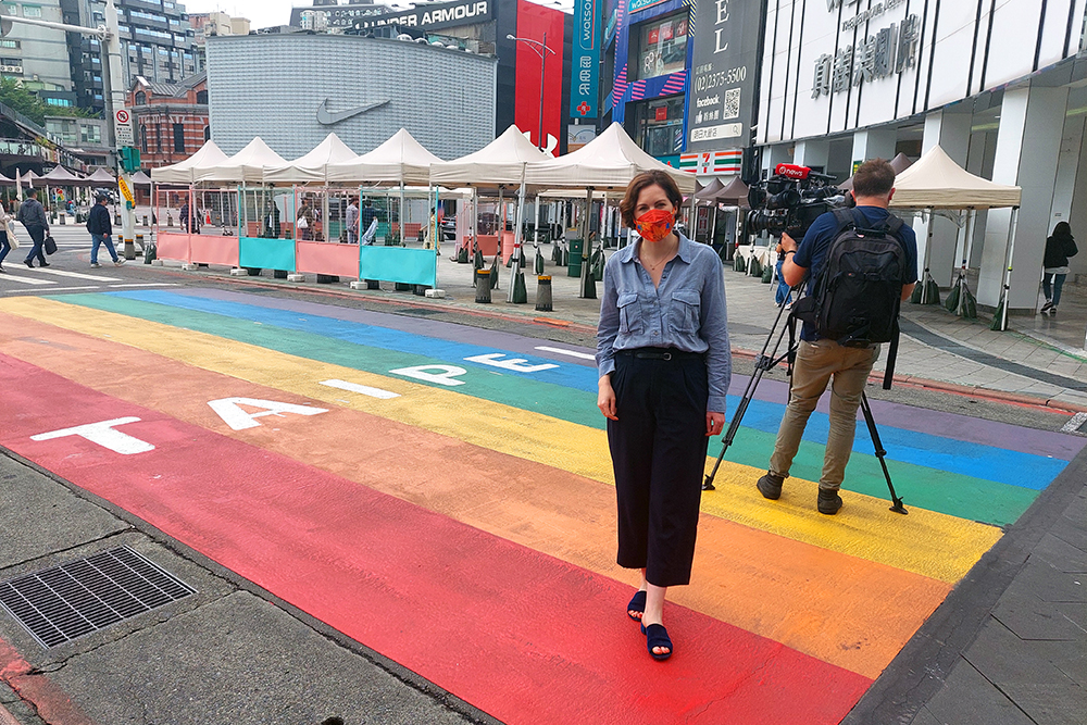 Cushla Norman standing on a large rainbow flag painted on the pavement with Taipei written across it