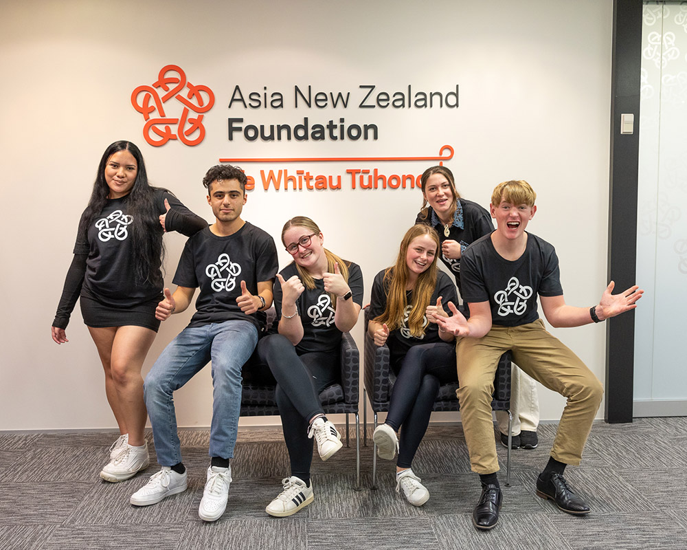 The Foundation team posing for a group photo in front of Asia New Zealand Foundation signage