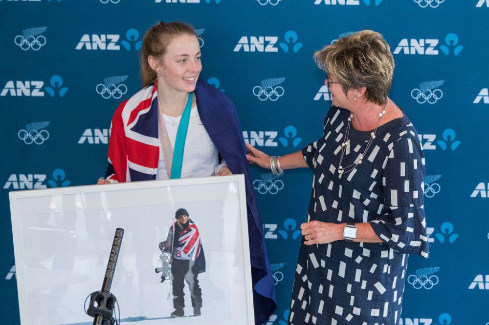 kereyn talking to a young athlete who is holding a large photo of herself with a snowboard and is draped in the NZ flag