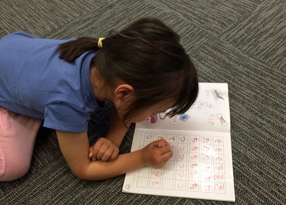 Young girl writes in Japanese characters