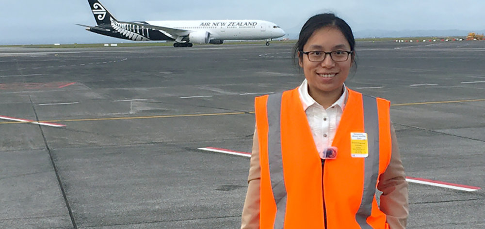 Sally chen at auckland airport on the runway with ar nz plane behind her