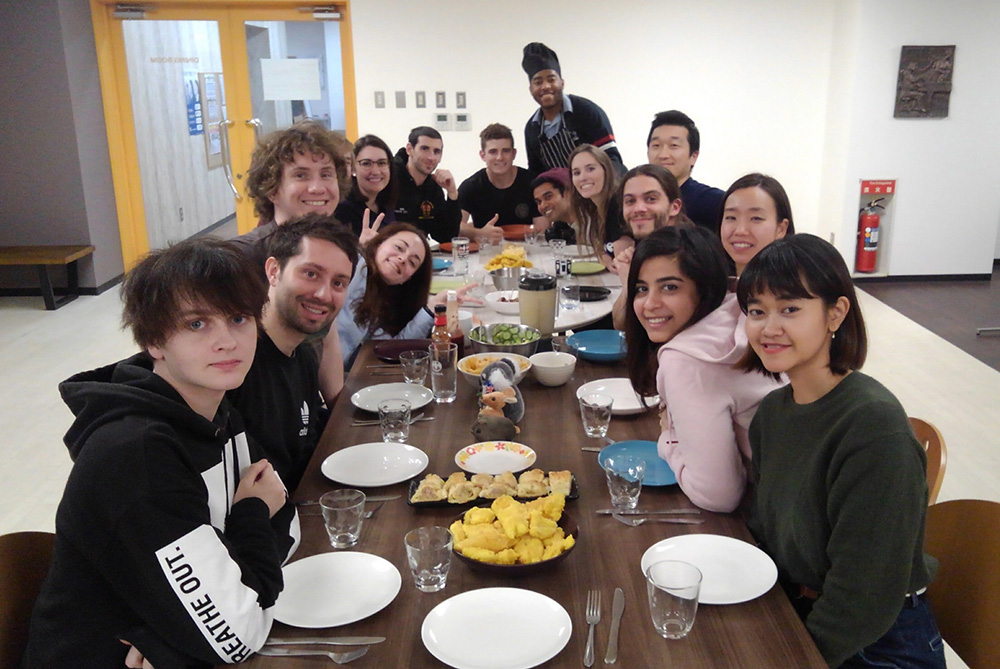 A large dinner table with a group of 15 young people sitting at it