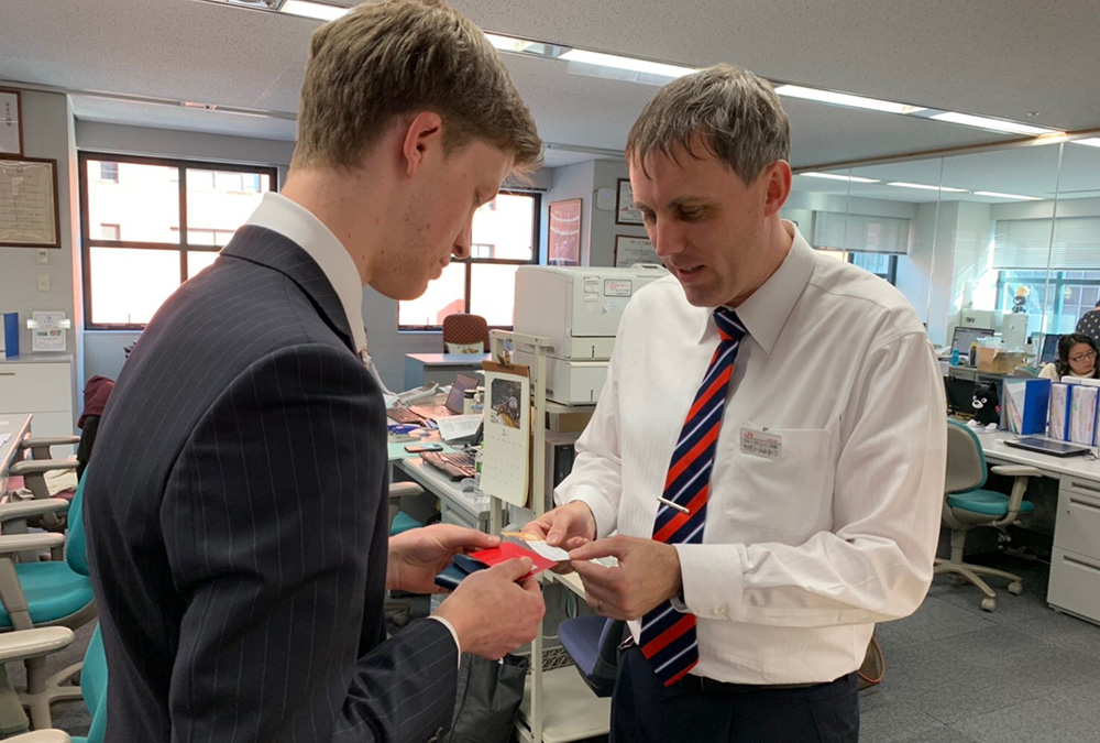 Benjamin exchanging business cards with a colleague