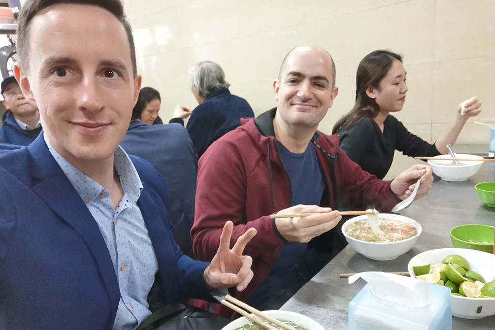Leadership Network member Ben O'Brien sitting at a table eating noodles with friends
