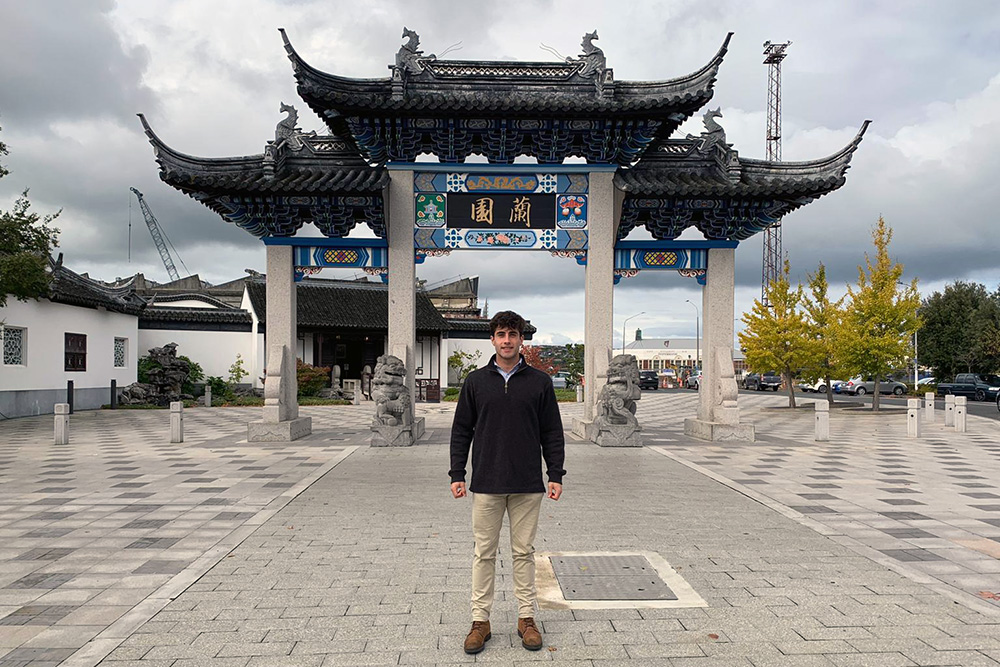 Cooper standing in front of a traditional Chinese gate