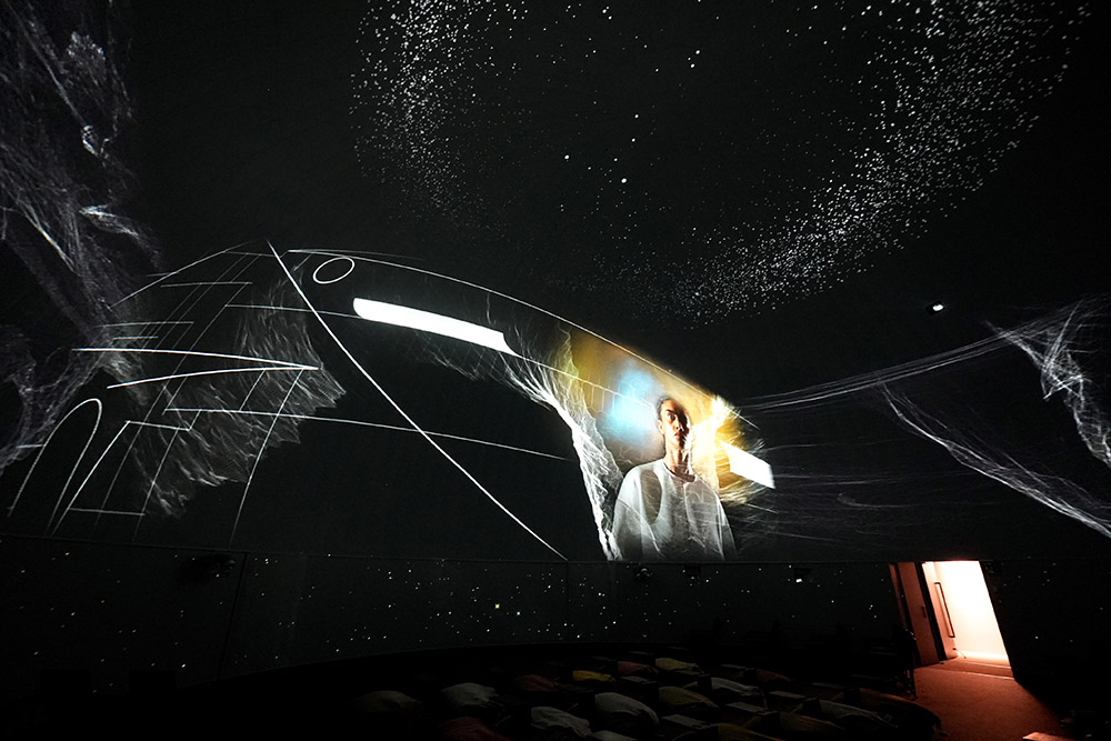 an image of a person among shapes and stars projected onto a ceiling