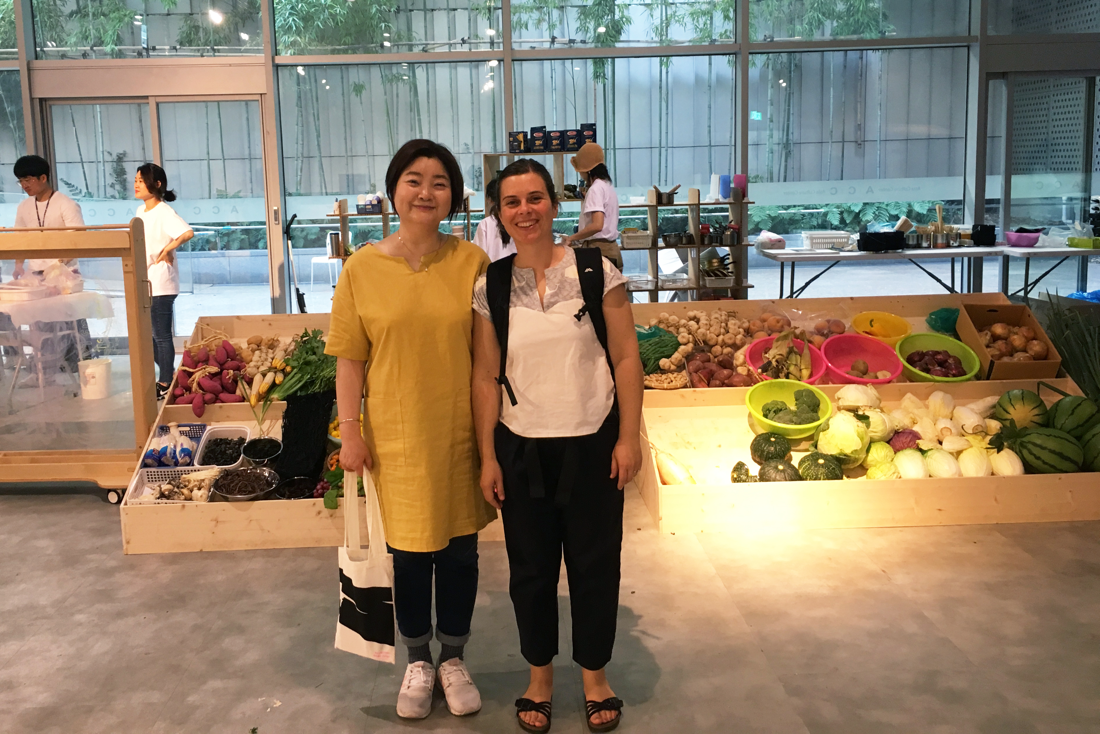 Nolwenn standing with a woman in front of an exhibition of vegetables