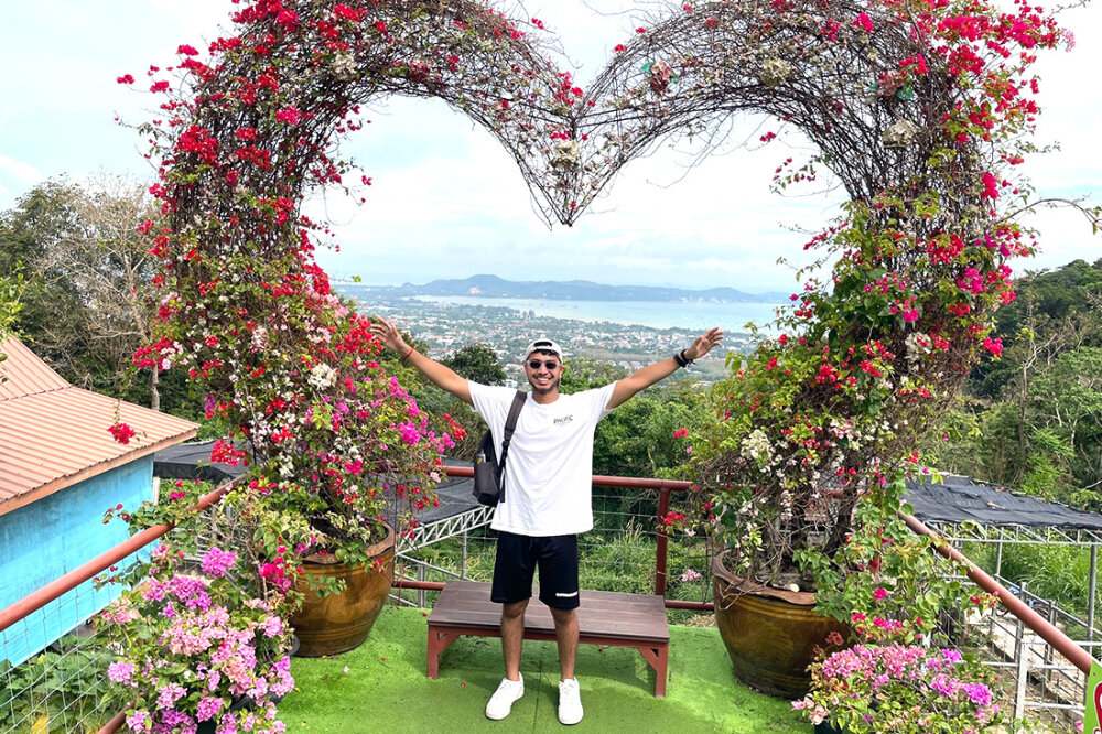 Siveshearn Jaynessh standing under a giant heart formed from vines covered in flowers