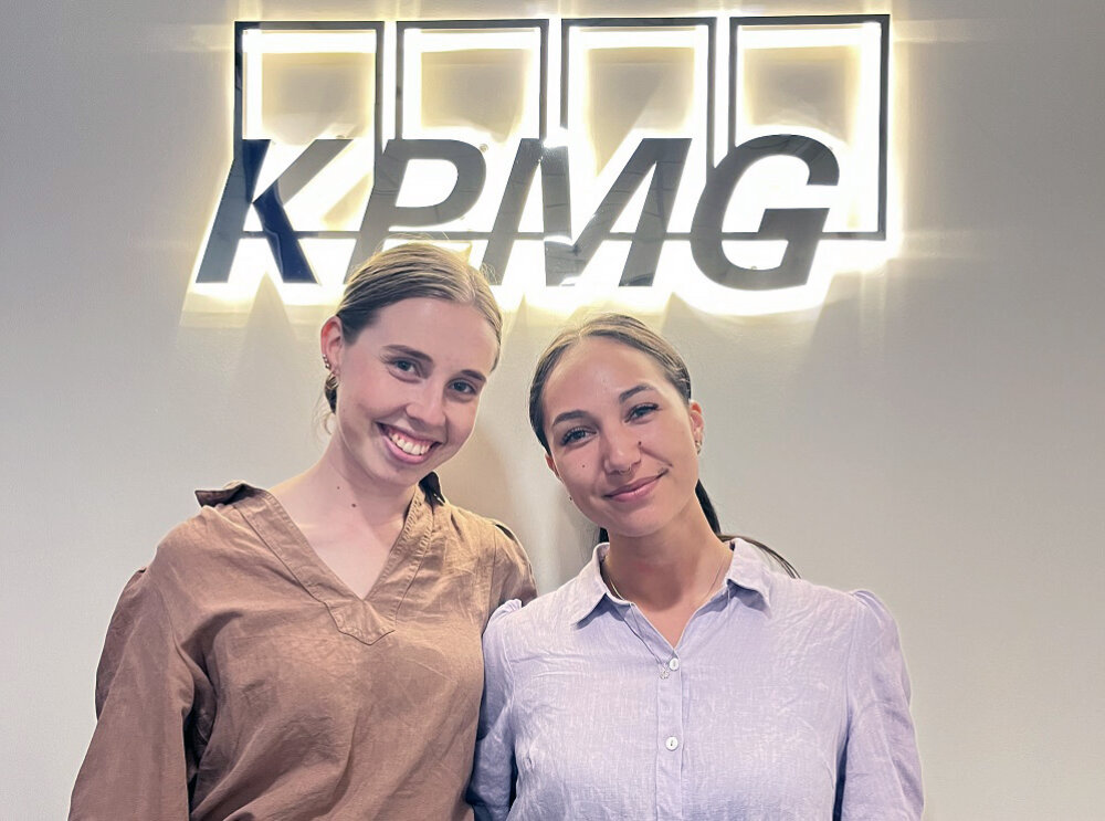 Harriet in front of a KPMG sign with fellow KPMG intern Cassidy Ray-Matthews