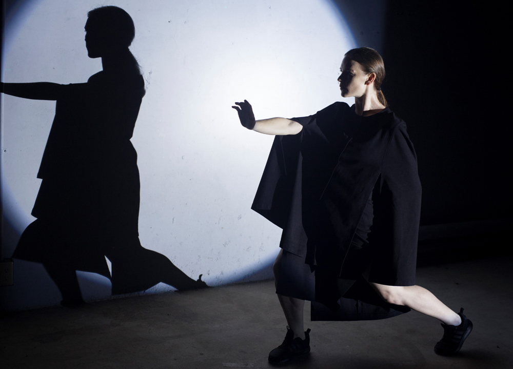 Woman dancing with arm out in front of spotlight