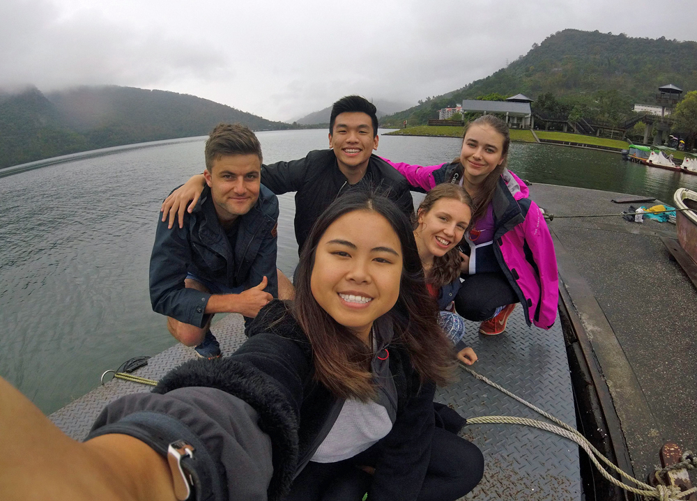 Young woman takes a photo with four friends by a lake