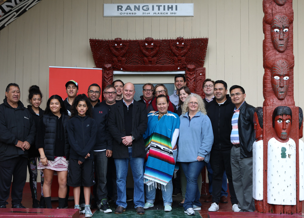 Foundation members and marae congregation standing in front of whare