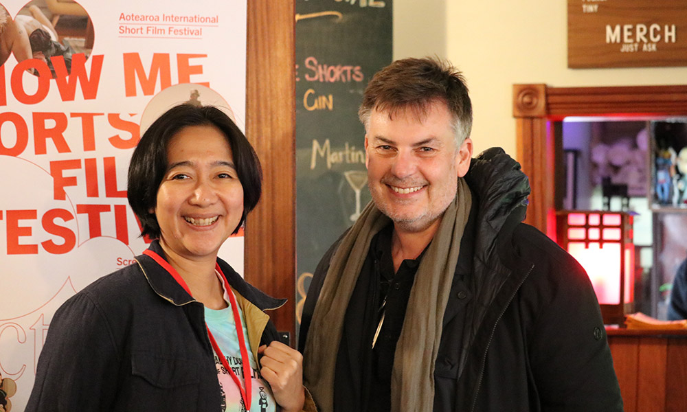 Programme director of Minikino, Fransiska Prihadi and Asia New Zealand Foundation's arts director Craig Cooper in front of a Show Me Shorts poster