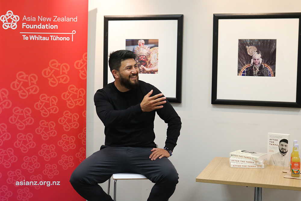 Abbas sitting on a stool and about about to speak at an Asia New Zealand Foundation event