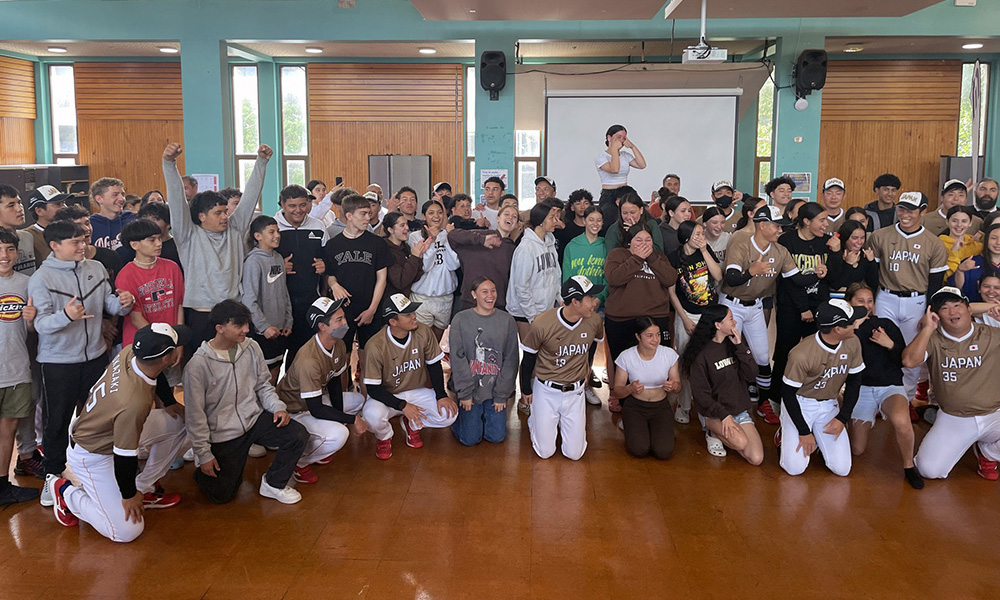 Japanese players and students pose for a group photo in a school hall