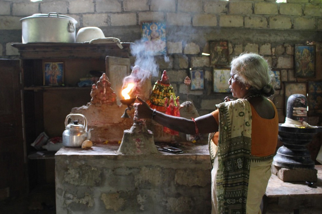 A woman lighting a lamp at a home shrine