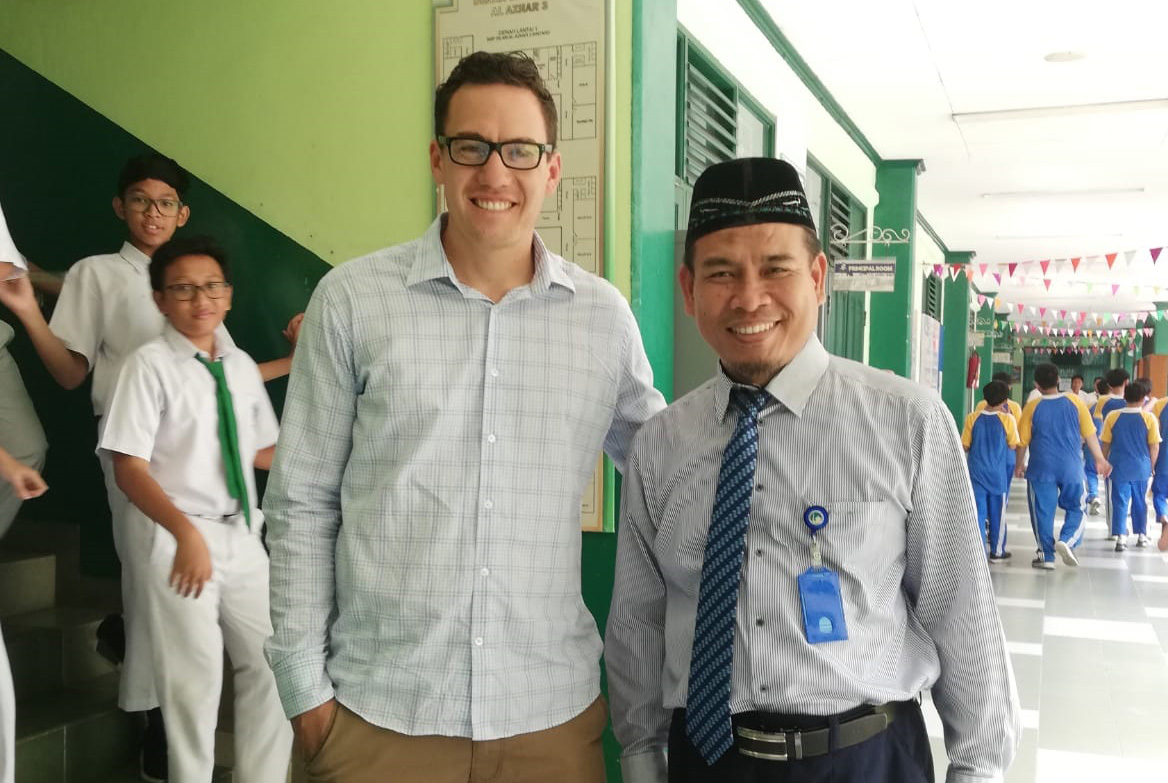 Kim Teo standing beside an Indonesian teacher in a school corridor