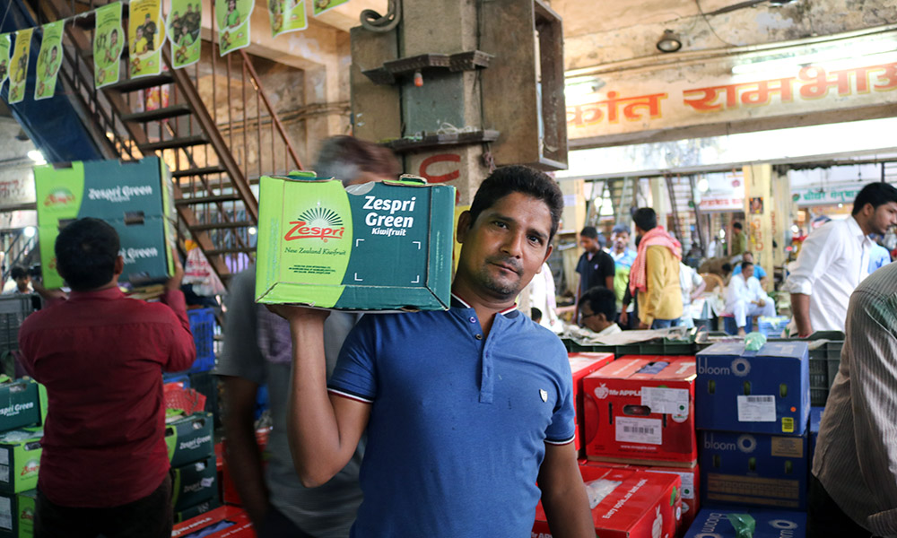 A man holding a box of Zespri kiwifruit in an Indian market