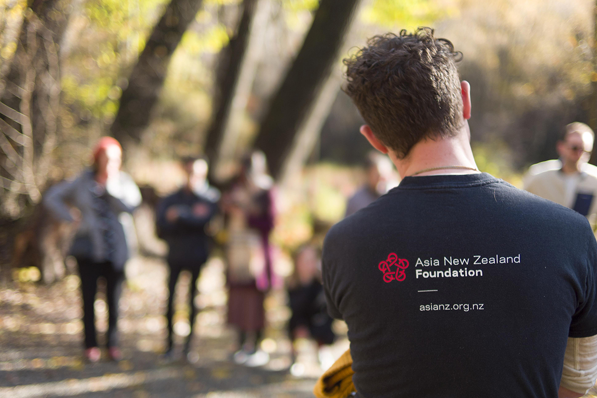 A man wearing an Asia New Zealand Foundation top with Leadership Network members standing in the background