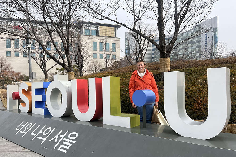 Libby standing beside large colourful letters spelling Seoul U