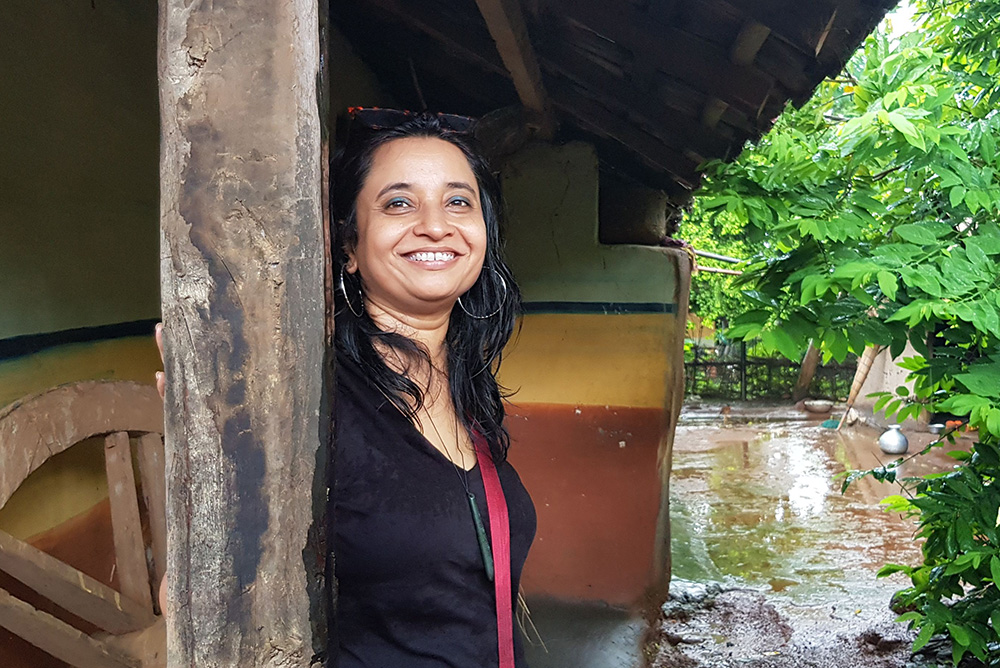 Liptika standing under a porch with the rain falling