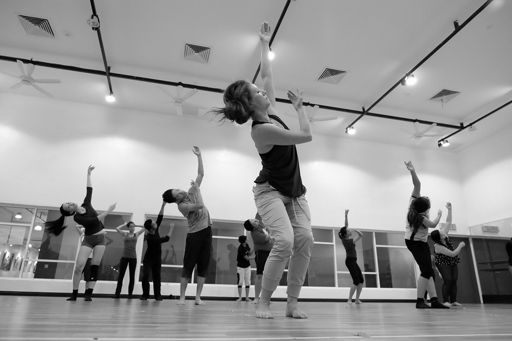 Lucy dancing in a studio leading fellow dancers