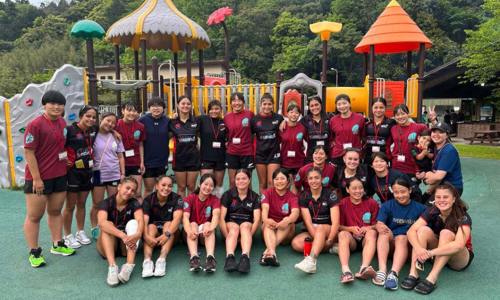 The Manukura team posing in front of a children's playgraound with a Japanese team