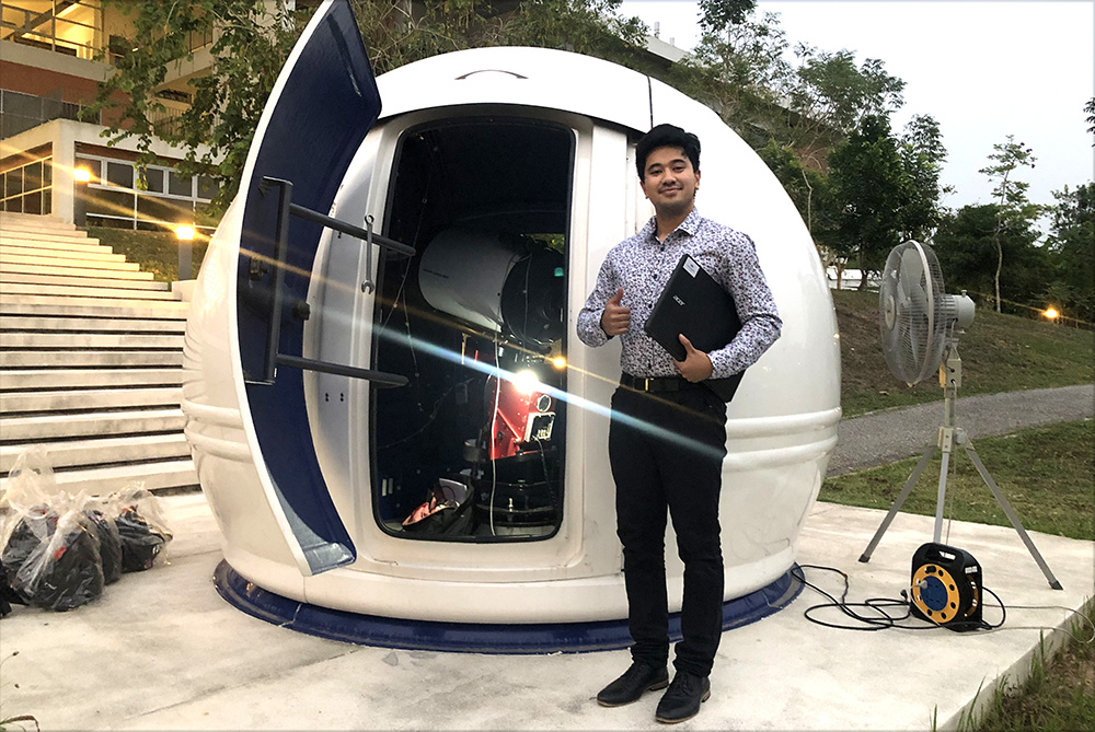 Mikhael standing beside a dome telescope