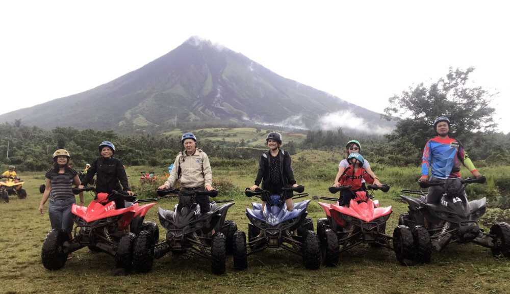 Five people on quad bikes with a volcanic mountain in the background