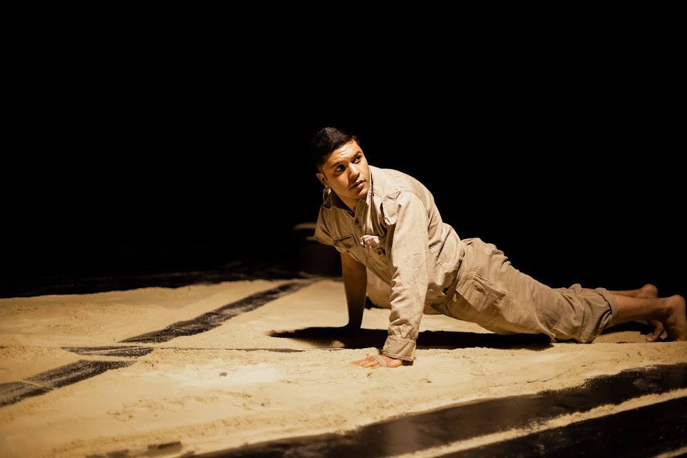 A man lying on a stage covered in sand
