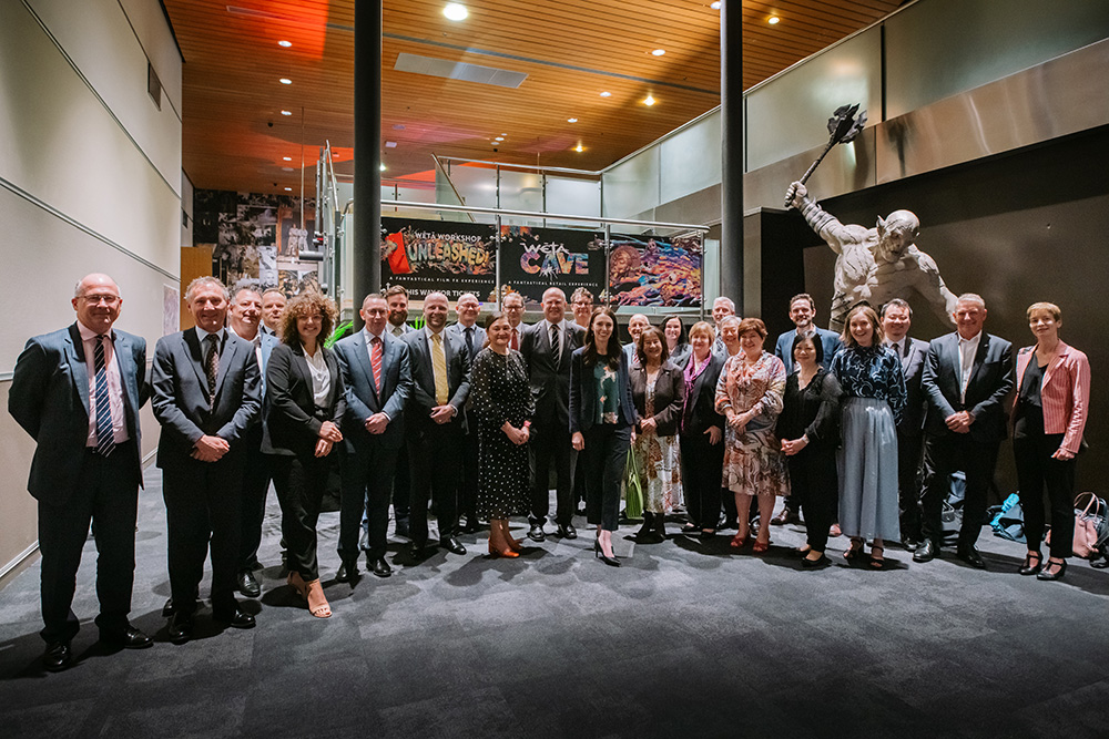 A group photo of about 30 people, including former prime minister Jacinda Ardern, in a foyer 
