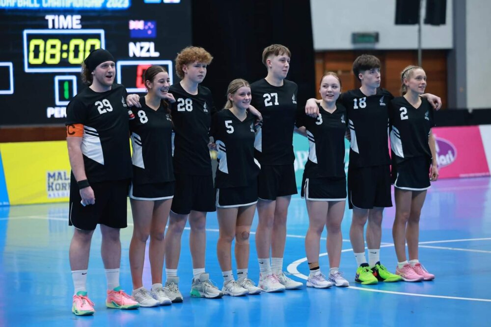 Eight of the players standing on a court in their black New Zealand strips