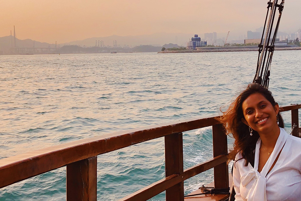 Naushyn on the deck of a boat with a  city skyline behind her