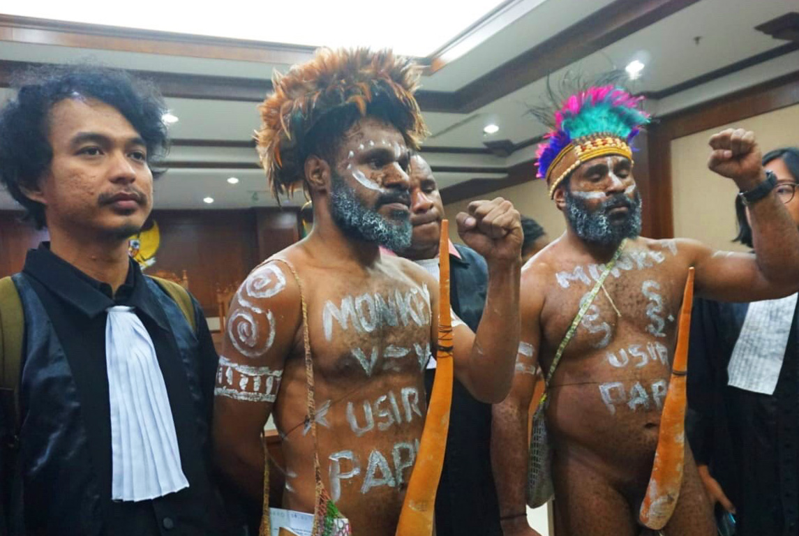Two Papuan activists daubed in slogans wearing traditional headdress and penis gauds