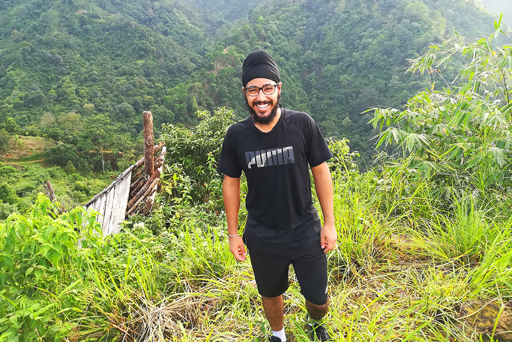 Parneet standing in front of a lush green hillside