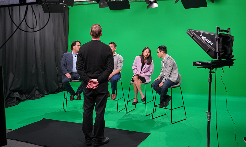 Three of the visiting entrepreneurs sitting on stools in a television studio waiting to be interviewed by Auckland Chamber of Commerce chief executive Simon Bridges