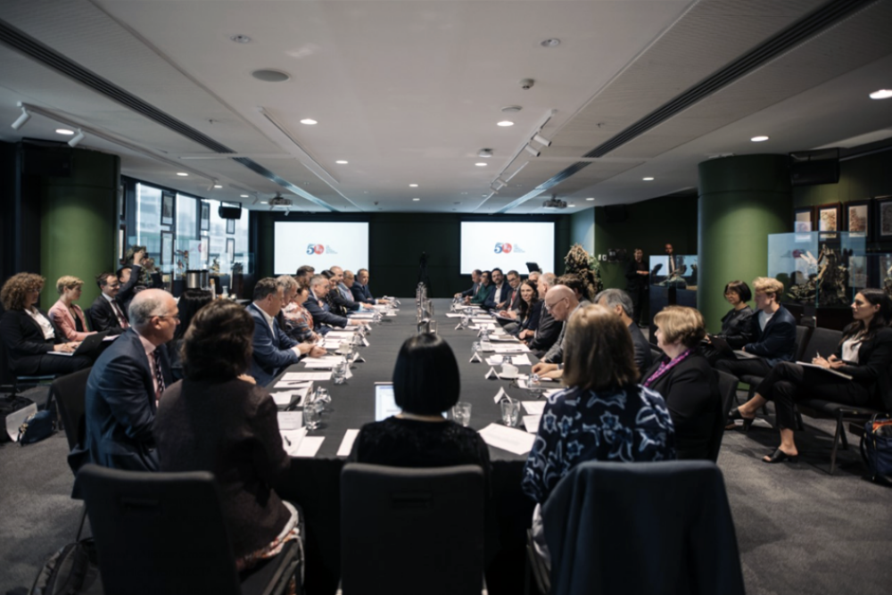A photo of a boardroom with 30-40 people in it aound a large table